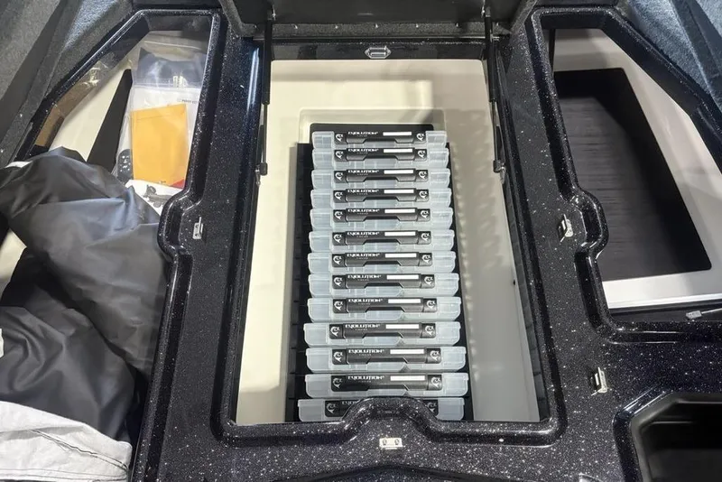 Slide: The Image of Storage compartment in a 2026 Skeeter ZXE20 boat, featuring organized tackle boxes. - 12