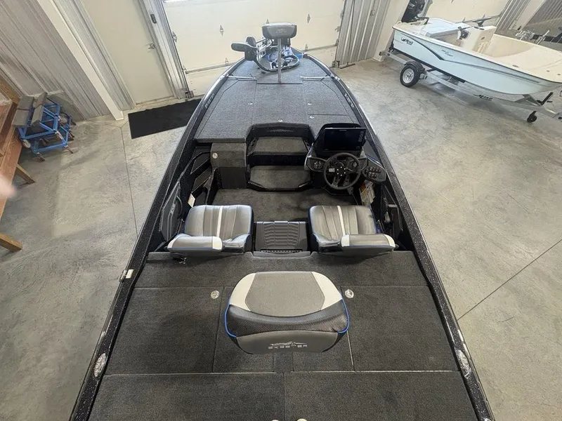 Slide: The Image of 2026 Skeeter ZXE20 boat interior with dual seats and steering console in a garage setting. - 24