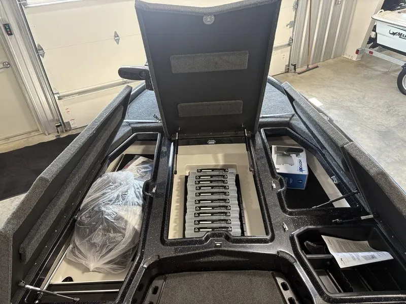 Slide: The Image of 2026 Skeeter ZXE20 boat interior with open storage compartments in a garage setting. - 3