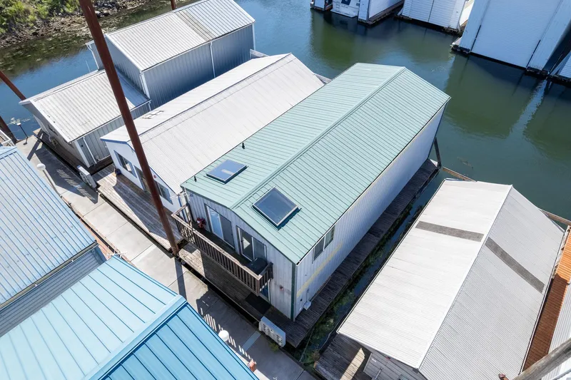 The Image of Aerial view of a 1970 custom boathouse with a green roof on calm water. - 1