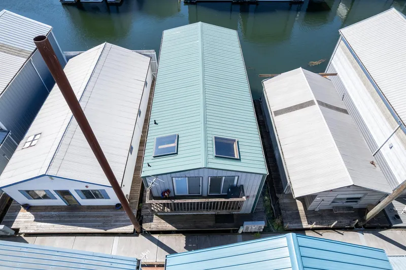 Slide: The Image of Aerial view of a 1970 custom boathouse with a green roof, docked between two others. - 11