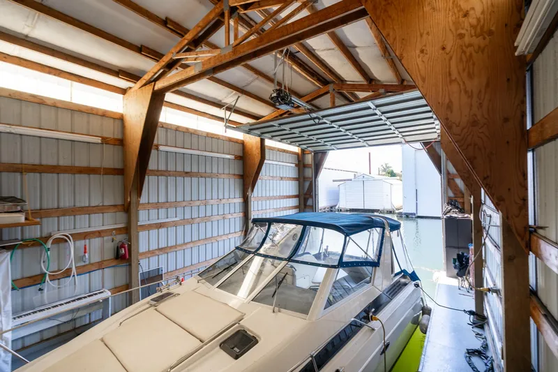 Slide: The Image of Interior of a 1970 custom boathouse with a docked boat and open garage door. - 5