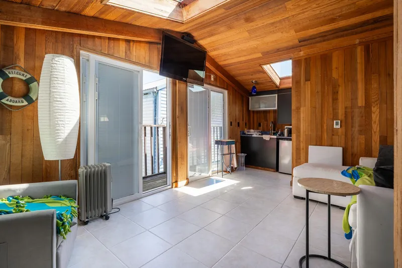 Slide: The Image of Cozy 1970 custom boathouse interior with wood paneling, modern furniture, and natural light. - 6