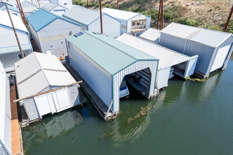 Slide: The Image of Aerial view of custom 1970 boathouses on calm water, featuring blue and white structures. - 9