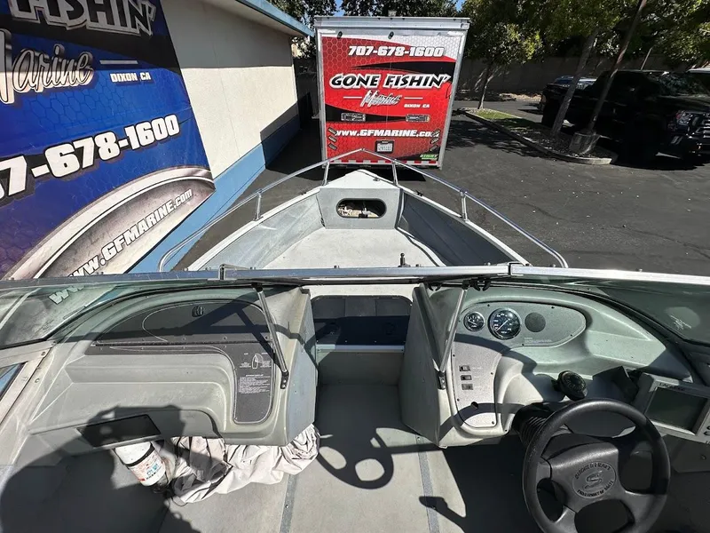 Slide: The Image of 2001 Smoker Craft 160 SP boat interior with steering wheel and dashboard, parked near a marine shop. - 22