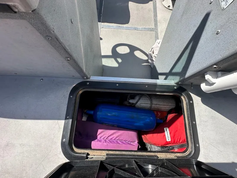 Slide: The Image of Storage compartment in 2001 Smoker Craft 160 SP boat with various items inside. - 26