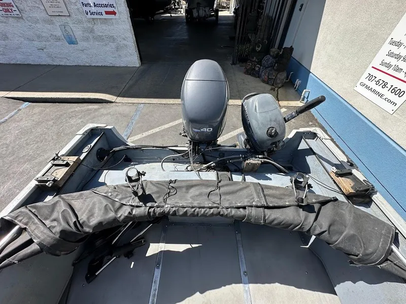 Slide: The Image of 2001 Smoker Craft 160 SP boat with outboard motor, parked near a marine service center. - 9