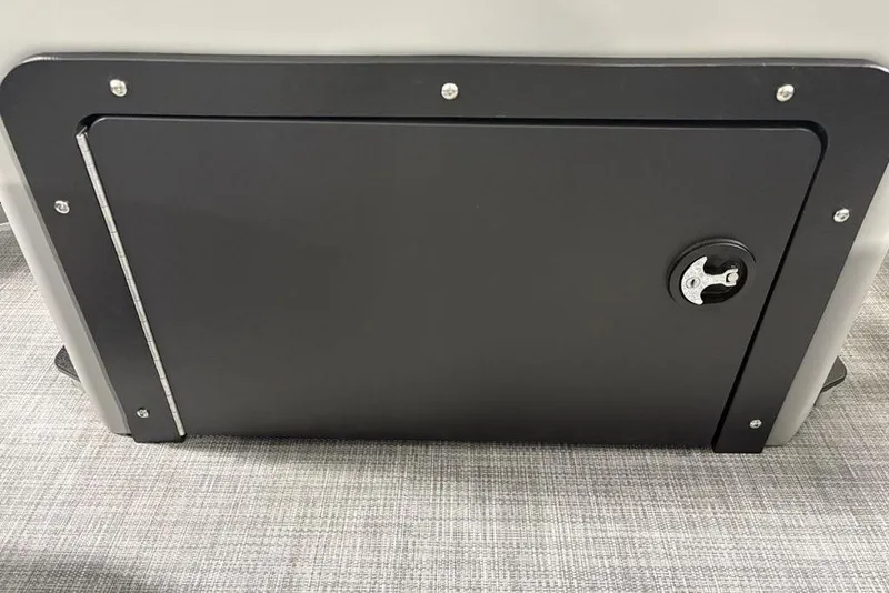 Slide: The Image of 2026 Sun Tracker SportFish™ 22 DLX storage compartment with secure latch on carpeted floor. - 18