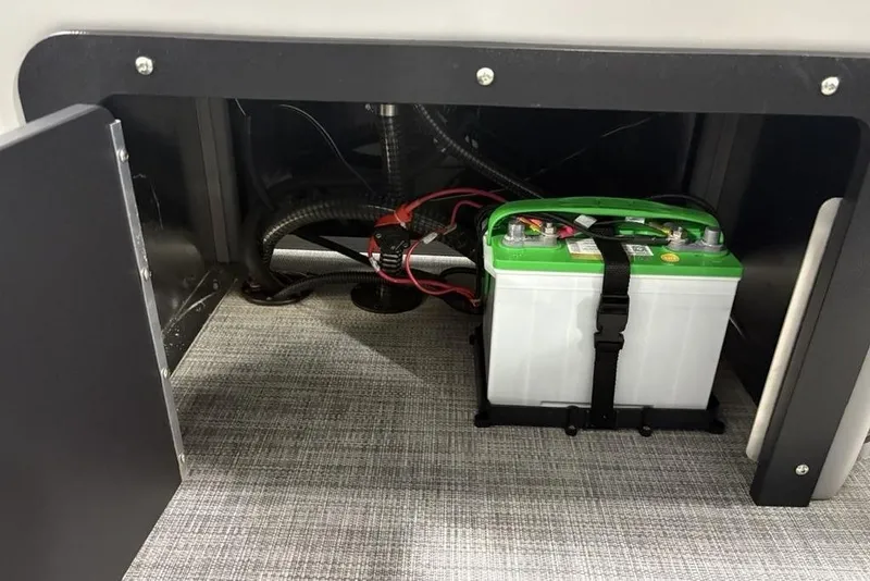 Slide: The Image of Battery compartment of 2026 Sun Tracker SportFish™ 22 DLX, featuring secured green-top battery. - 19