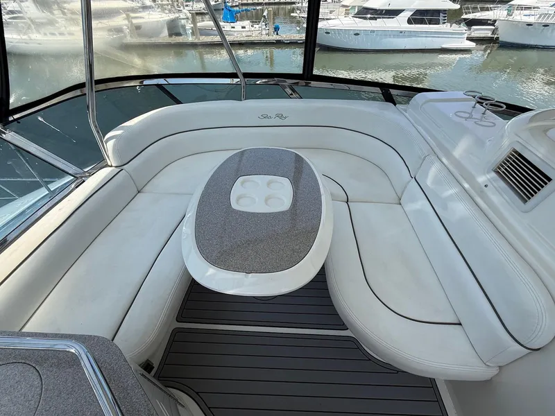 Slide: The Image of 2007 Sea Ray 52 Sedan Bridge yacht interior with white seating and table, docked at marina. - 12