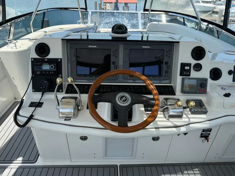 Slide: The Image of 2007 Sea Ray 52 Sedan Bridge helm with dual screens and wooden steering wheel. - 15