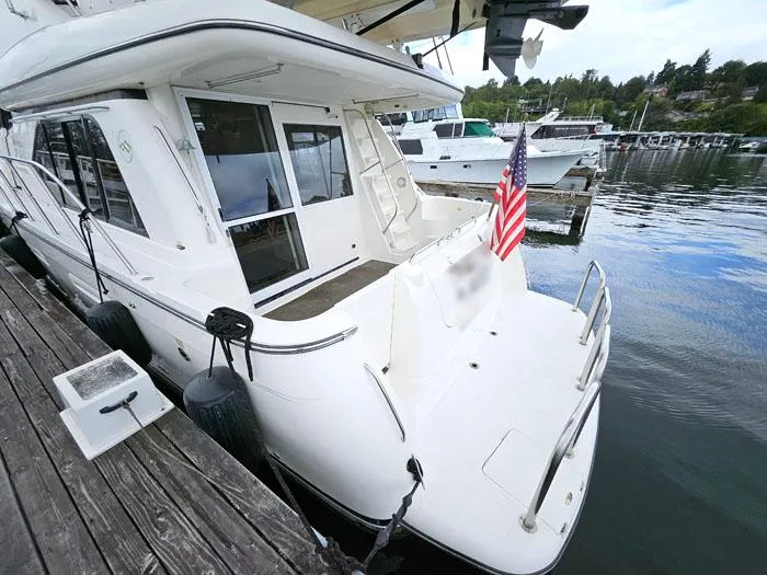 Slide: The Image of 2000 Bayliner 5288 Pilot House Motoryacht docked with American flag, rear view. - 4