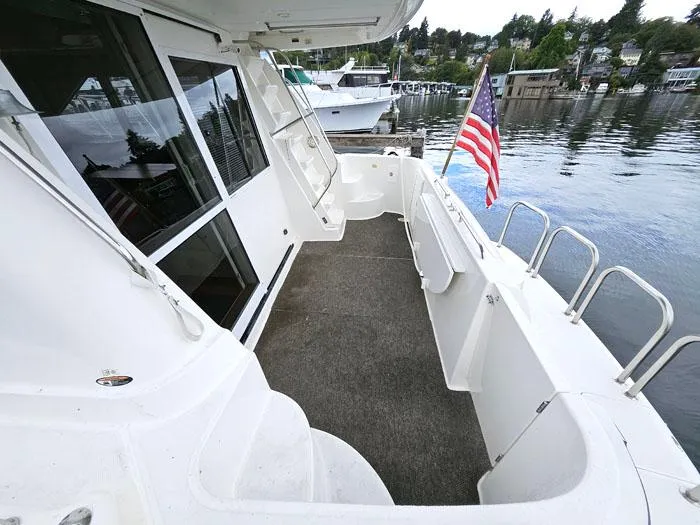Slide: The Image of Bayliner 5288 Pilot House Motoryacht 2000, spacious deck with American flag, docked by waterfront. - 5
