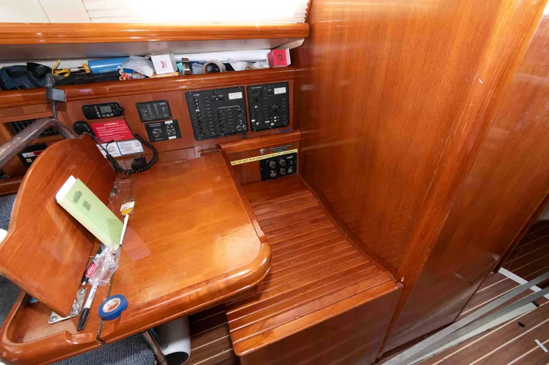 Slide: The Image of 2006 Hunter 44 Deck Salon navigation station with wooden finish and control panels. - 11
