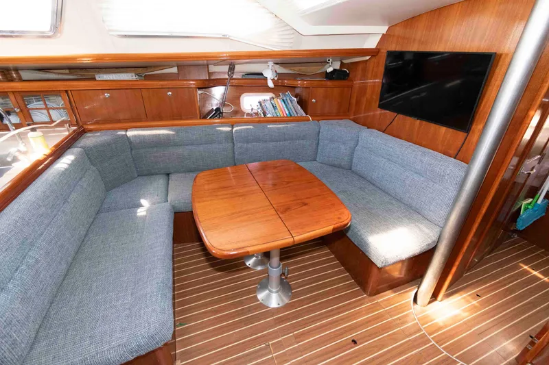 Slide: The Image of 2006 Hunter 44 Deck Salon interior with cozy seating, wooden table, and mounted TV. - 9