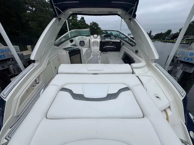 Slide: The Image of 2013 Monterey 328 Super Sport boat interior with white seating and dashboard, docked by the water. - 11
