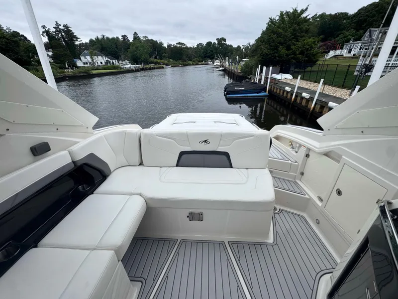 Slide: The Image of 2013 Monterey 328 Super Sport boat interior with white seating, docked by a scenic river. - 18