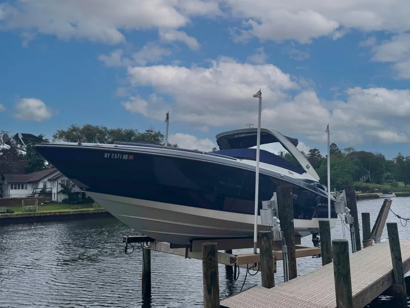 Slide: The Image of 2013 Monterey 328 Super Sport boat docked on a lift by a scenic river. - 2