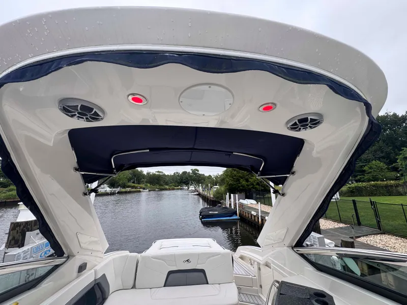 Slide: The Image of 2013 Monterey 328 Super Sport boat interior with canopy, docked by a scenic waterway. - 20