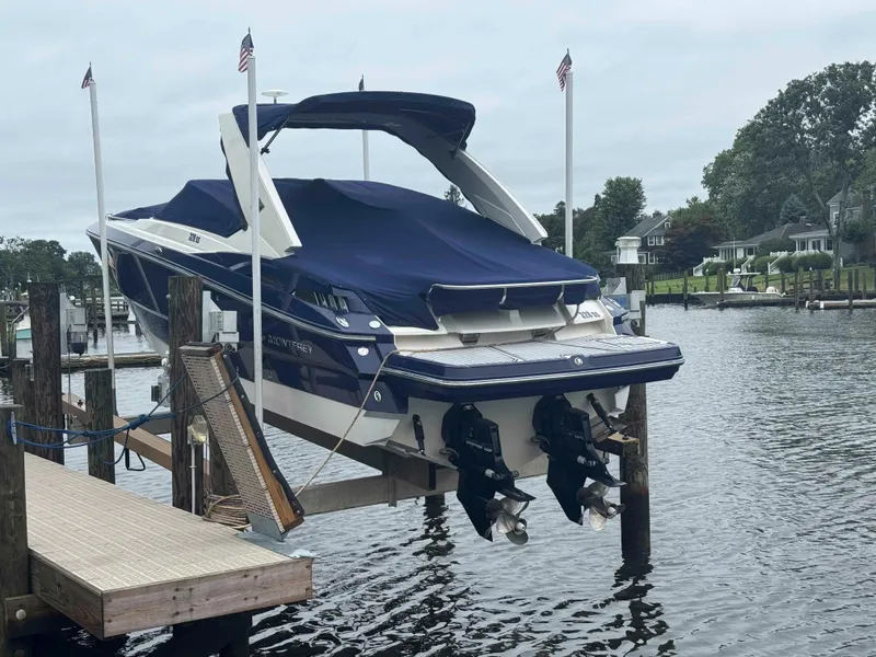 Slide: The Image of 2013 Monterey 328 Super Sport boat docked, covered, with dual engines, in a serene marina setting. - 4