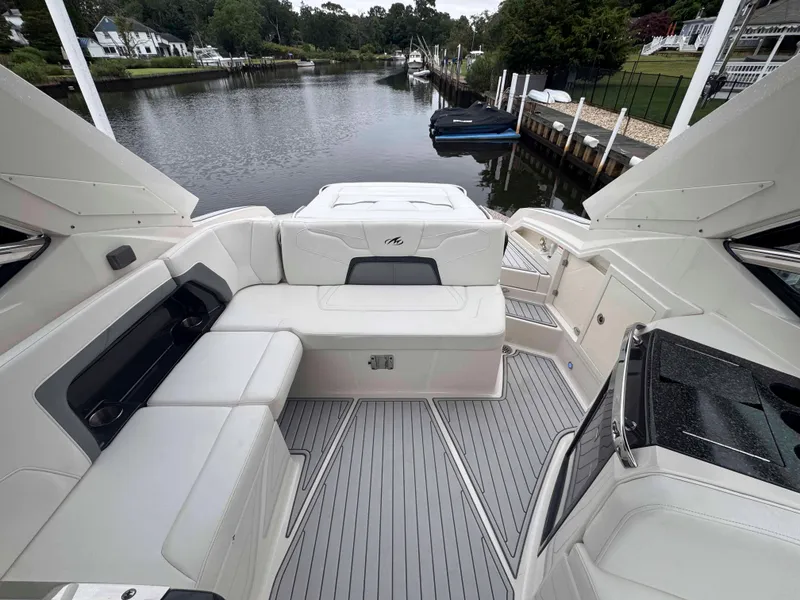 Slide: The Image of 2013 Monterey 328 Super Sport boat interior with white seating, docked by a serene waterfront. - 43