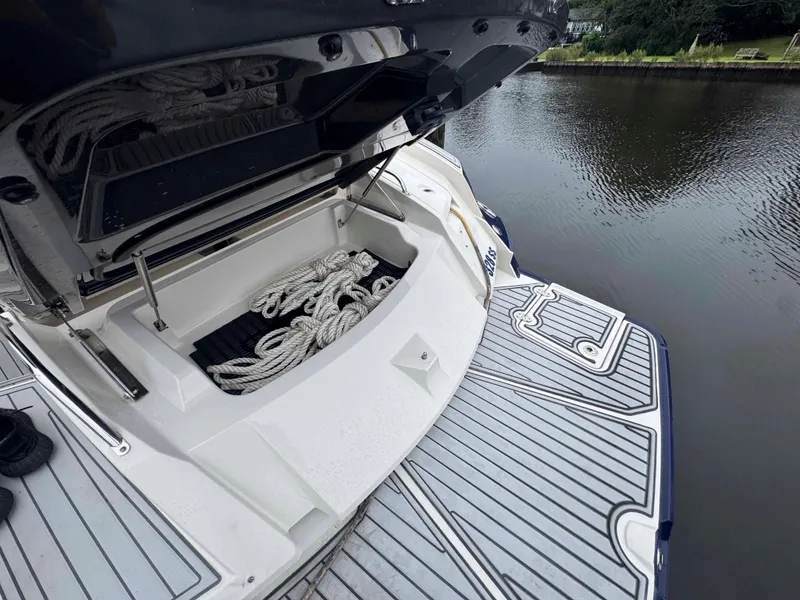 Slide: The Image of 2013 Monterey 328 Super Sport boat with open storage compartment and ropes by the water. - 44