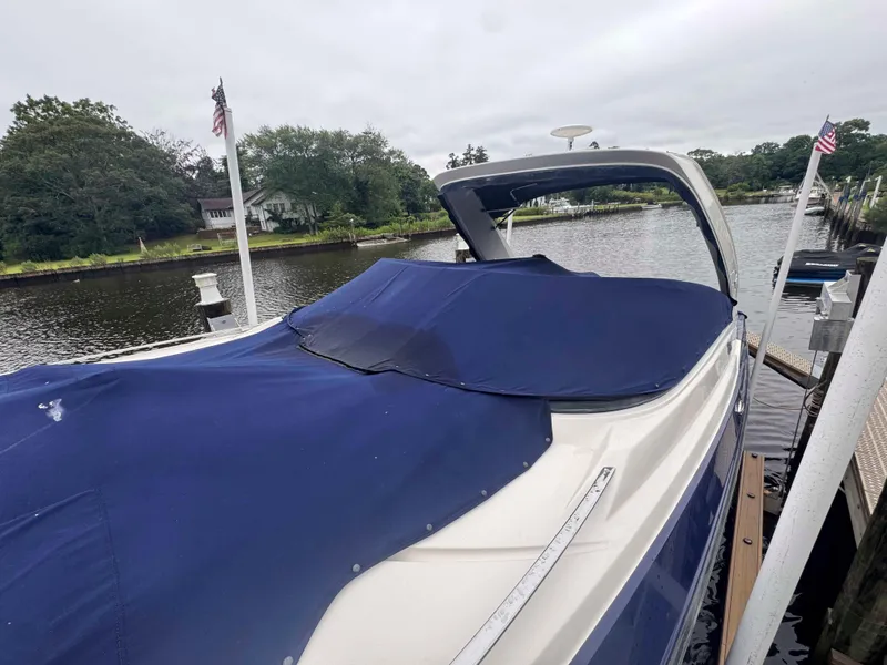 Slide: The Image of 2013 Monterey 328 Super Sport boat docked with blue cover, surrounded by water and greenery. - 8