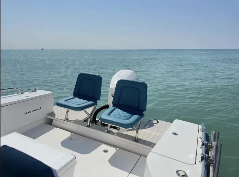 Slide: The Image of 2020 Axopar 28 TT boat with blue seats on calm ocean water. - 12