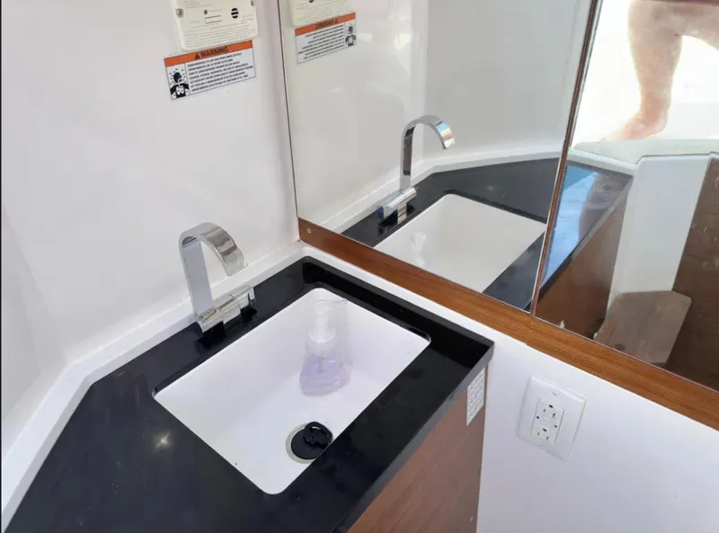 Slide: The Image of 2020 Axopar 28 TT boat bathroom sink with modern faucet and mirror. - 26