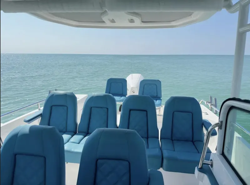 Slide: The Image of 2020 Axopar 28 TT boat interior with blue seating, overlooking calm ocean waters. - 9