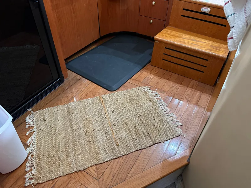 Slide: The Image of Interior of 1999 Sea Ray 400 Sedan Bridge with wooden flooring and woven rug. - 16
