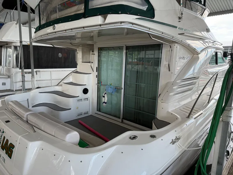 Slide: The Image of 1999 Sea Ray 400 Sedan Bridge yacht docked, featuring spacious deck and sliding glass doors. - 2