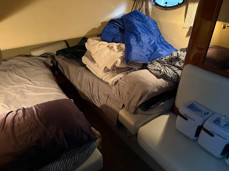 Slide: The Image of Interior cabin of 1999 Sea Ray 400 Sedan Bridge with cozy bedding and porthole window. - 23