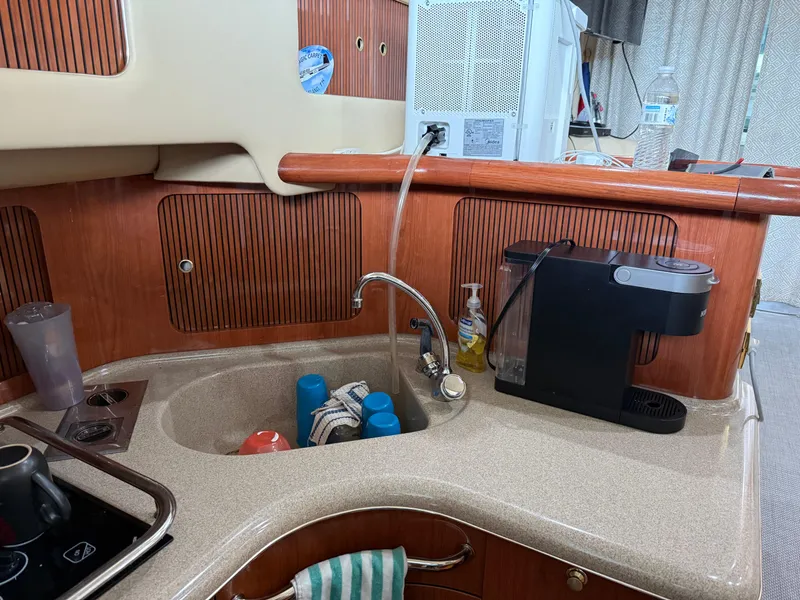 Slide: The Image of 1999 Sea Ray 400 Sedan Bridge kitchen with sink, coffee maker, and wooden cabinetry. - 24