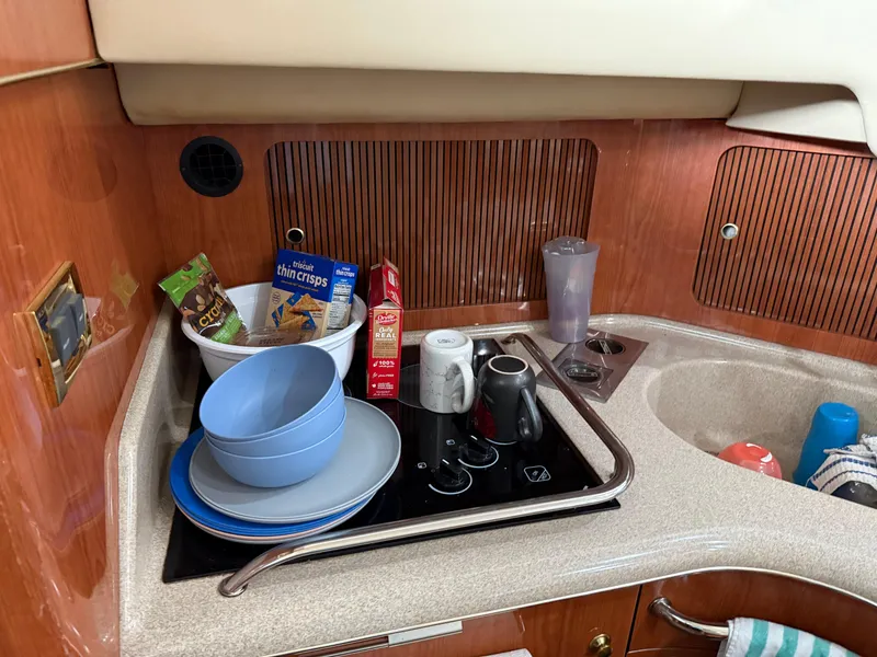 Slide: The Image of 1999 Sea Ray 400 Sedan Bridge kitchen with snacks, bowls, and mugs on the counter. - 25