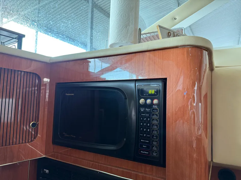 Slide: The Image of 1999 Sea Ray 400 Sedan Bridge interior with Panasonic microwave in wooden cabinetry. - 26