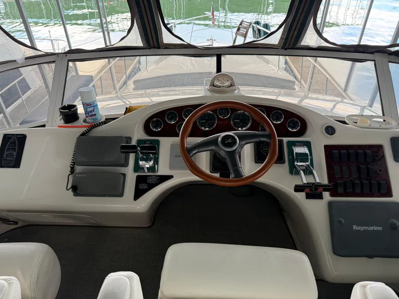 Slide: The Image of 1999 Sea Ray 400 Sedan Bridge helm with steering wheel and control panel. - 43