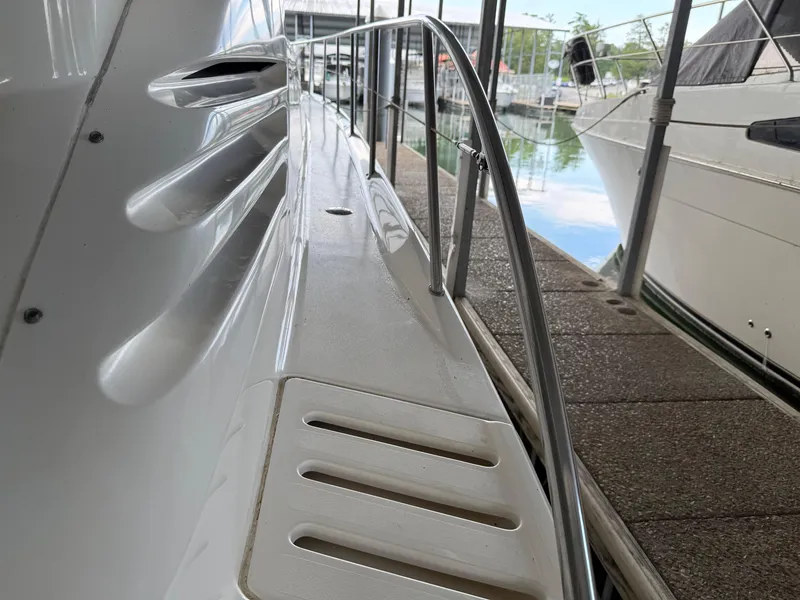 Slide: The Image of 1999 Sea Ray 400 Sedan Bridge yacht docked, showing sleek side deck and railing. - 6
