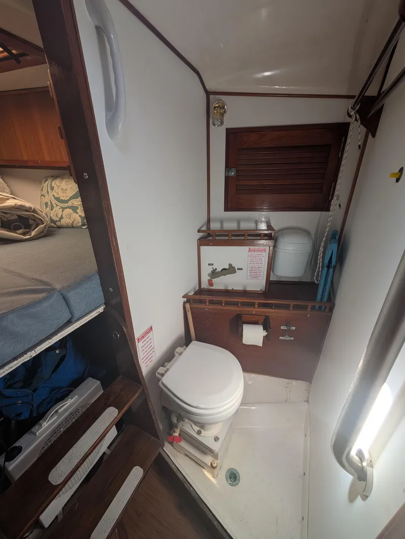 Slide: The Image of Compact bathroom in a 1976 Mason COHORT II boat, featuring a toilet and wooden accents. - 10