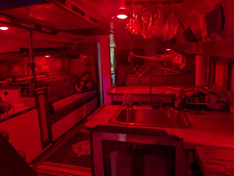 Slide: The Image of Red-lit interior of a 1976 Mason COHORT II yacht, featuring a cozy kitchen and seating area. - 9