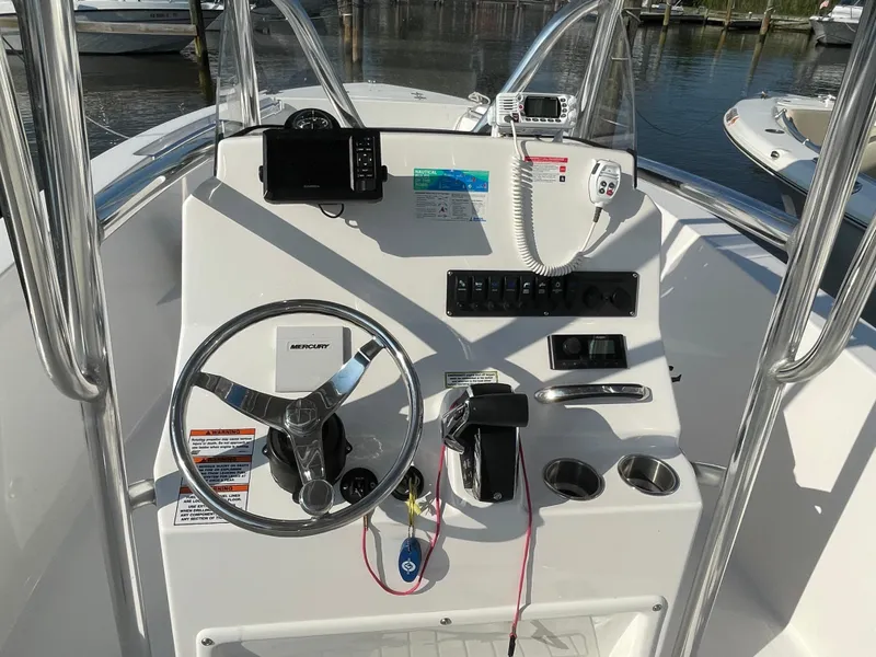 Slide: The Image of 2024 Aquasport 2200 Center Console boat dashboard with steering wheel and controls. - 6