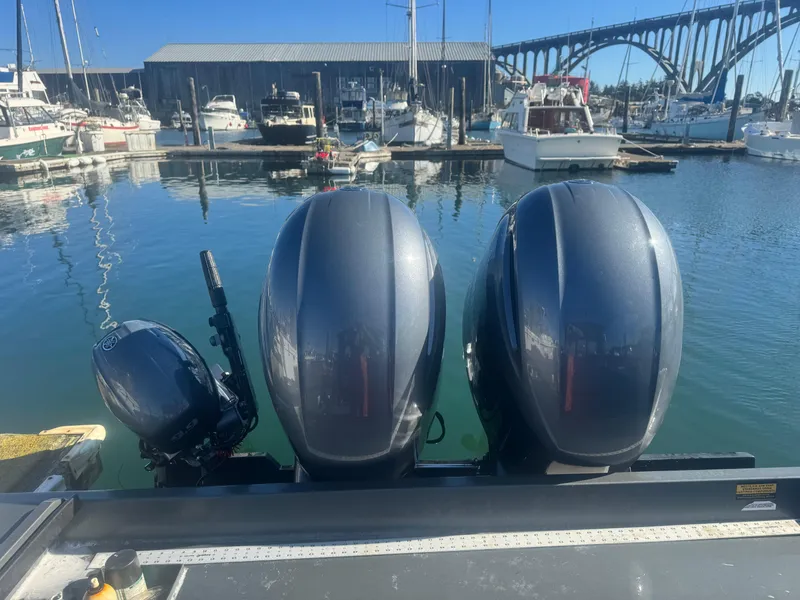 Slide: The Image of Three outboard motors on a 2022 Custom Umpqua Marina 26 bay series boat at a marina. - 9