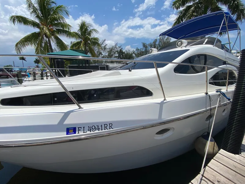 Slide: The Image of Azimut 46 yacht from 2000 docked, with palm trees and blue sky in the background. - 14