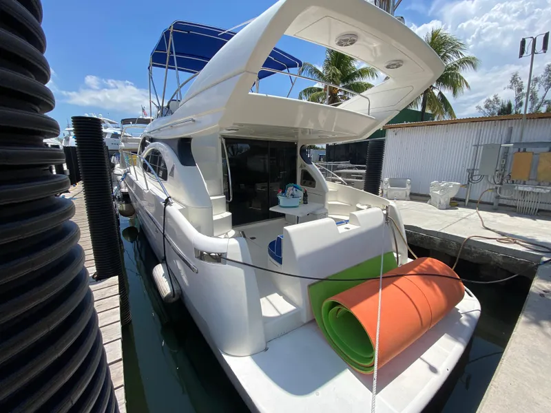 Slide: The Image of Azimut 46 yacht from 2000 docked, featuring a spacious deck and vibrant rolled mats. - 17