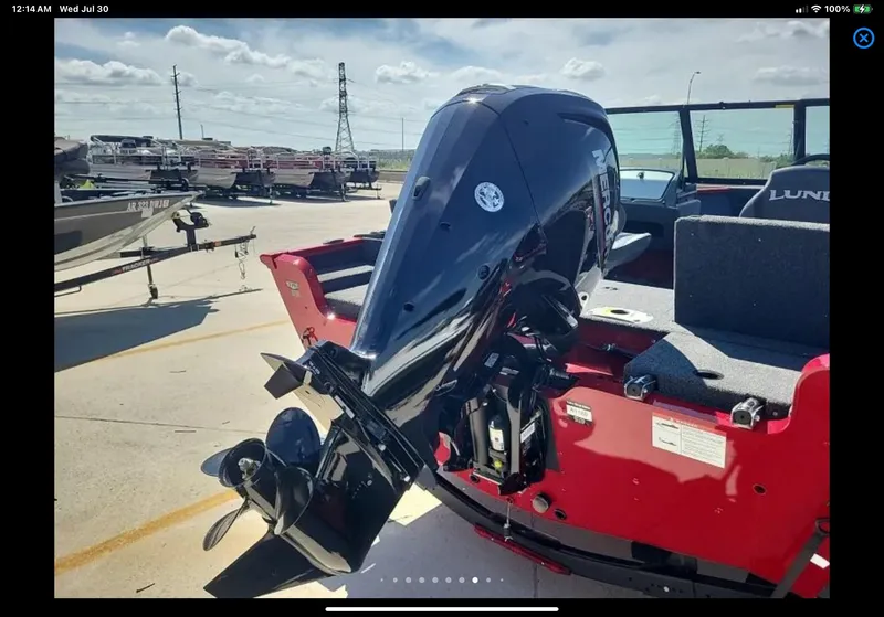 Slide: The Image of 2024 Lund 1675 Adventure Sport boat with powerful outboard motor in a sunny marina. - 11