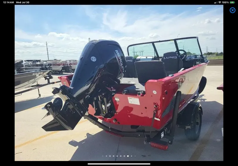 Slide: The Image of 2024 Lund 1675 Adventure Sport boat with outboard motor, parked on a sunny day. - 15