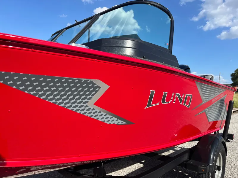 Slide: The Image of 2024 Lund 1675 Adventure Sport boat, red exterior, close-up view, clear sky background. - 3