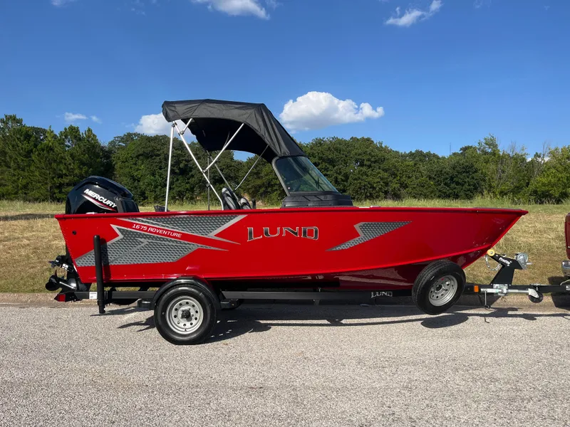Slide: The Image of 2024 Lund 1675 Adventure Sport boat in vibrant red on a trailer, parked outdoors. - 4
