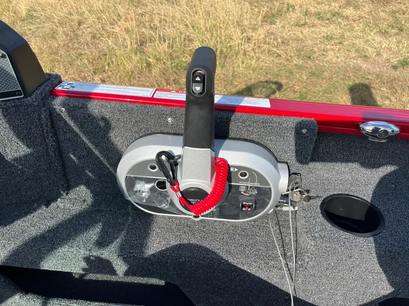 Slide: The Image of 2024 Lund 1675 Adventure Sport boat throttle control with red safety lanyard on carpeted deck. - 41