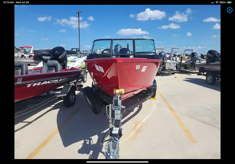 Slide: The Image of 2024 Lund 1675 Adventure Sport boat in a dealership lot under a clear blue sky. - 5